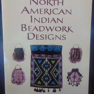 May include: Book cover with the title "North American Indian Beadwork Designs" by Clark Wissler. The cover features five beaded bags with intricate geometric patterns in shades of brown, red, blue, green, and yellow.