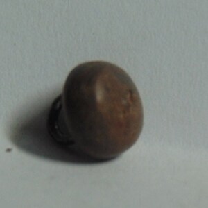 May include: A small, round, brown metal bell with a loop on the side.