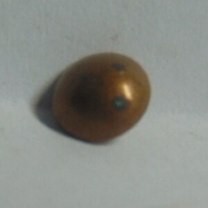 May include: A small, round, copper-colored button with a green center.