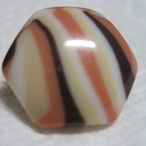 May include: A hexagonal button with a swirl pattern in shades of brown, white, and pink.