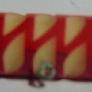 May include: A red and white striped plastic toy with a zig-zag pattern.