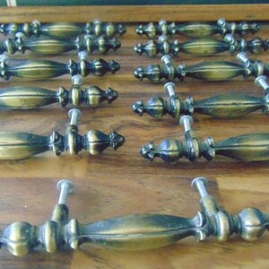 May include: A set of 12 antique brass cabinet knobs with a decorative, ornate design. The knobs have a classic, vintage look and would be a great addition to any home.