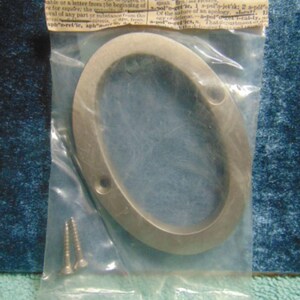 May include: A brushed silver metal house number zero in a clear plastic bag with two small mounting screws. The packaging features a header card with printed dictionary definitions. The number has two pre-drilled holes for installation.