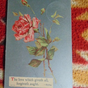 May include: A vintage postcard with a blue background featuring a single red rose with green leaves and a quote that reads "The love which giveth all, forgiveth aught. - Bailey."