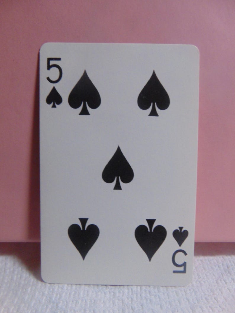 May include: A standard playing card with a white background and black spades. The card is a five of spades.
