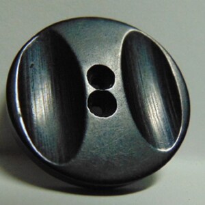 May include: A black plastic button with two holes. The button has a smooth, rounded surface with a slight indentation in the center.