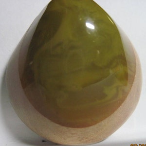 May include: A green and brown teardrop-shaped resin paperweight with a smooth, glossy finish.