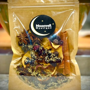May include: A clear, resealable bag filled with dried herbs, spices, and fruit slices. The bag features a circular label with the text "Moonveil Mystique" and a crescent moon design. Ingredients include cinnamon sticks, star anise, and dried berries.
