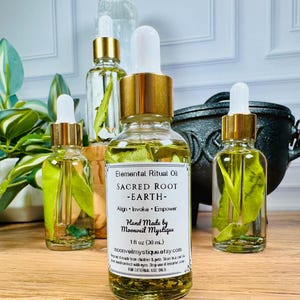 May include: Three clear glass dropper bottles filled with yellow oil and green leaves. The central label reads Elemental Ritual Oil, SACRED ROOT -EARTH-, Align, Invoke, Empower, Hand Made by Moonveil Mystique, 1 fl oz (30 mL), moonveilmystique.etsy.com.