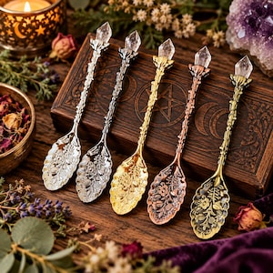 May include: Five metal spoons with intricate floral embossed bowls and twig-textured handles, each topped with a clear, pointed crystal point. The set includes finishes in polished silver, dark gunmetal, bright gold, copper, and antique brass.