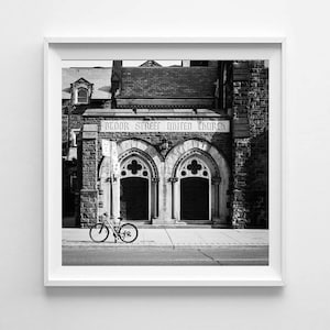May include: Monochrome photograph of a church with arched doorways and the text "Bloor Street United Church" above the entrance. A bicycle is parked on the pavement in front of the church.