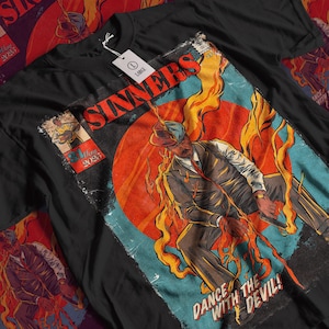 Puede incluir: Camiseta negra con un diseño gráfico retro. El diseño presenta la palabra "SINNERS" en rojo, un hombre con traje rodeado de llamas y el texto "DANCE WITH THE DEVIL!" junto con una fecha.