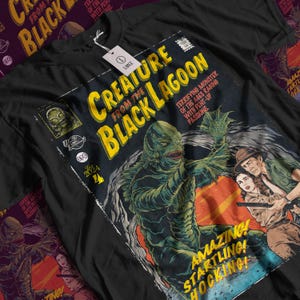 Puede incluir: Camiseta negra con un diseño de cómic de la Criatura de la Laguna Negra. El diseño incluye el texto "Creature from the Black Lagoon" en amarillo, junto con ilustraciones de la criatura y otros personajes. La camiseta tiene una etiqueta de talla grande.