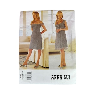May include: A pattern for two women's dresses with a floral print. The dresses are knee-length and have different necklines. The pattern is labeled "ANNA SUI" and includes sizing information.