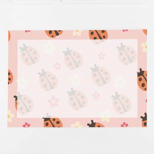 Op de afbeelding: Een roze briefpapier set met een lieveheersbeestje en bloemen patroon. Het ontwerp bevat oranje en zwarte lieveheersbeestjes, witte en roze bloemen en een witte rand. Een witte pen ligt aan de rechterkant van het briefpapier.