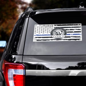 May include: A rectangular sticker featuring a distressed American flag design with a blue line. The sticker includes a circular emblem with a bulldog and the text "HUMANIZING THE BADGE" and "CODE 4".