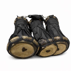 Peut inclure: Trois petits djemb&eacute;s avec du tissu noir tiss&eacute; et des peaux de tambour beiges. Les tambours sont reli&eacute;s par une attache m&eacute;tallique et des sangles noires. Les tambours sont pos&eacute;s sur un fond blanc.