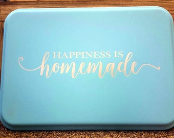 May include: A light blue baking pan with a white inscription that reads "Happiness is homemade".