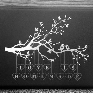 May include: Black and white graphic design of a tree with two birds perched on a branch. Hanging from the branches are hearts with the words "LOVE IS HOMEMADE" written on them.