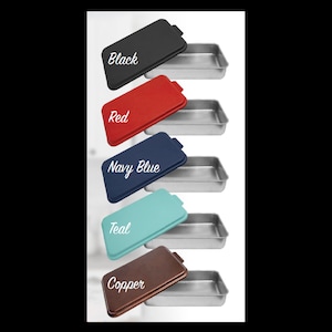 May include: Five different colored lids for a metal baking pan. The lids are black, red, navy blue, teal, and copper. The baking pan is silver.