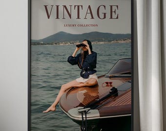 Op de afbeelding: Ingelijste print met het woord 'VINTAGE' en 'LUXURY COLLECTION'. Een persoon op een houten boot houdt een verrekijker vast. Ze draagt een marineblauwe jas en witte shorts. De achtergrond toont water en bergen. De afbeelding heeft een vintage esthetiek.