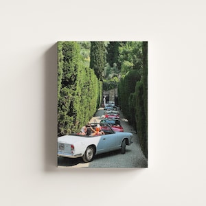 May include: A print depicting a line of classic convertible cars driving along a tree-lined path. The lead car is light blue, with passengers visible. The scene is bathed in sunlight, creating a nostalgic atmosphere. The image evokes a sense of vintage travel.
