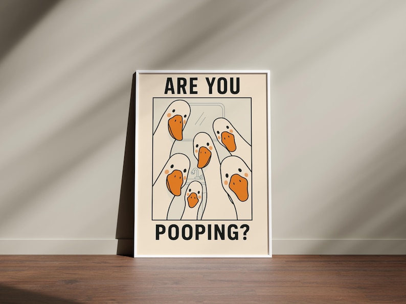 Op de afbeelding: Een ingelijste poster met een cr&egrave;mekleurige achtergrond toont een cartoonillustratie van verschillende witte ganzen met oranje snavels. De tekst "ARE YOU" staat bovenaan en "POOPING?" onderaan, wat een humoristisch ontwerp cre&euml;ert.