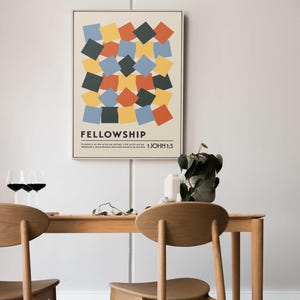 Könnte beinhalten: Gerahmtes Poster mit dem Wort „FELLOWSHIP“ und dem Bibelvers 1. Johannes 1:3. Das Kunstwerk zeigt ein geometrisches Design aus farbigen Quadraten in Blau-, Gelb-, Orange- und Dunkelgrüntönen. Das Poster wird über einem Holztisch mit zwei Stühlen angezeigt.