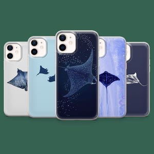 Op de afbeelding: Vijf telefoonhoesjes met illustraties van manta's. De hoesjes tonen verschillende ontwerpen, waaronder een sterrenhemel, een lichtblauwe achtergrond met meerdere roggen en een aquareleffect. De manta's zijn afgebeeld in tinten blauw en wit.