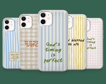 Puede incluir: Una colección de fundas para teléfonos con varios patrones y citas inspiradoras. Los diseños incluyen rayas azules y blancas, cuadros y el texto "God's timing is perfect". Las fundas están en fila sobre un fondo verde.