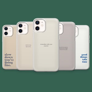 以下が含まれることがあります： さまざまなニュートラルカラーの5つの携帯電話ケース。それぞれに黒いテキストで異なるインスピレーションを与える引用句が書かれています。ケースは一列に並んでおり、「なぜ始めたのかを覚えておいてください」や「良いことは時間がかかる」などの引用句が含まれています。