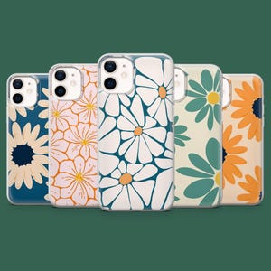 Puede incluir: Cinco fundas para teléfono con diseños de margaritas. Las fundas presentan patrones florales en blanco, naranja, azul y verde. Cada funda tiene un borde transparente. El fondo es verde oscuro.
