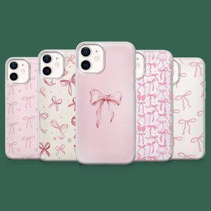 May include: A collection of five phone cases with a pink bow theme. The cases feature various designs, including a single bow, and repeating bow patterns in shades of pink. The cases are displayed against a dark green background.