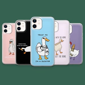 Könnte beinhalten: Eine Auswahl an Handyhüllen mit humorvollen Enten-Illustrationen. Die Hüllen sind in verschiedenen Farben, darunter Rosa, Schwarz und Blau, und tragen Slogans wie "Trust Me, I'm a Ducktor" und "Peace was never an option."