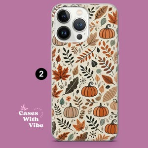 Puede incluir: Una funda de tel&eacute;fono con un dise&ntilde;o oto&ntilde;al. El dise&ntilde;o presenta calabazas naranjas, hojas marrones y naranjas, y follaje verde sobre un fondo crema. La funda tiene un borde transparente y el n&uacute;mero "2" en un c&iacute;rculo negro.