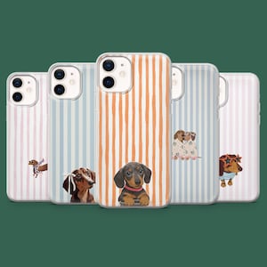 Puede incluir: Cinco fundas transparentes para teléfono con rayas verticales en rosa pastel, azul claro y naranja. Cada funda muestra una ilustración diferente de un perro salchicha, incluyendo uno con un lazo blanco, uno con collar rosa y otro con gafas de estrella.