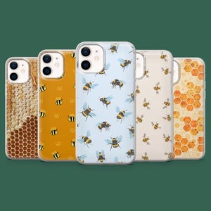 Puede incluir: Una colección de fundas para teléfonos con diseños de abejas. Las fundas presentan varios patrones, incluyendo panales, abejas con coronas y abejas sobre fondos azul claro y crema. Las fundas están diseñadas para un smartphone.