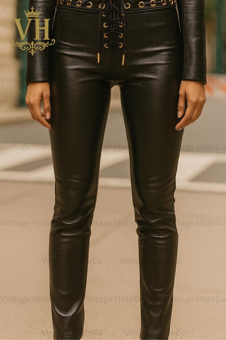 May include: Black leather pants with a lace-up detail at the waist. The pants are form-fitting and have a sleek, polished appearance. The image shows a close-up of the pants, highlighting the texture and design.