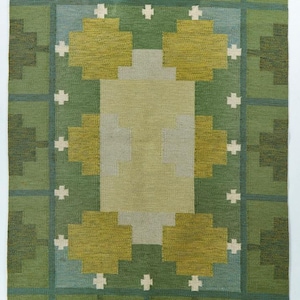 Op de afbeelding: Groen en beige rechthoekig vloerkleed met een geometrisch patroon. Het midden is lichtbeige, omringd door olijf- en donkergroene vormen. Witte kruisvormige details zijn gelijkmatig verdeeld. Het kleed heeft een franje aan de onderkant. Afmetingen circa 150 cm x 200 cm.