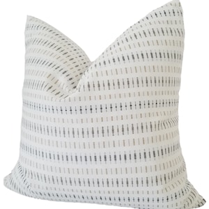 May include: White throw pillow with a geometric pattern in black, brown, and beige.