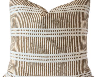 May include: Square throw pillow with a white background and a repeating pattern of vertical brown lines and dotted horizontal lines. The pillow has a soft, textured appearance and is likely made of fabric.