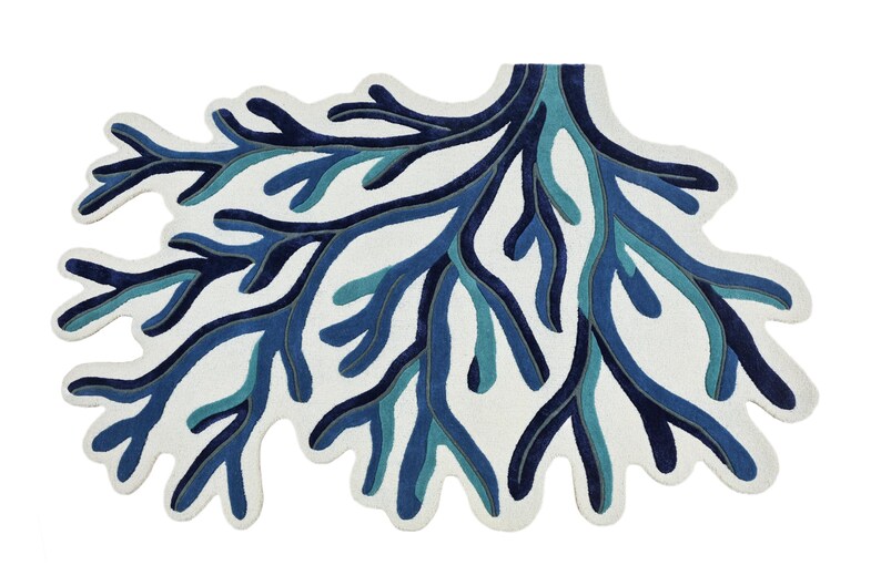 May include: A rug shaped like a branching coral structure featuring a white background with layered, organic patterns in shades of navy blue, royal blue, and teal. The design consists of intricate, interconnected limbs that spread outward.