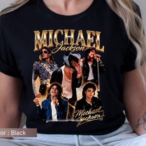 May include: Black t-shirt featuring a collage of images of Michael Jackson with the text "MICHAEL Jackson" in gold lettering. The shirt showcases various iconic poses of the artist, capturing his dynamic stage presence.