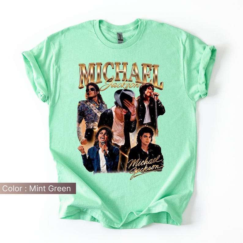 May include: Mint green t-shirt featuring a collage of images of Michael Jackson. The shirt has the words "MICHAEL Jackson" in gold lettering. The shirt is a crew neck and has rolled-up sleeves.