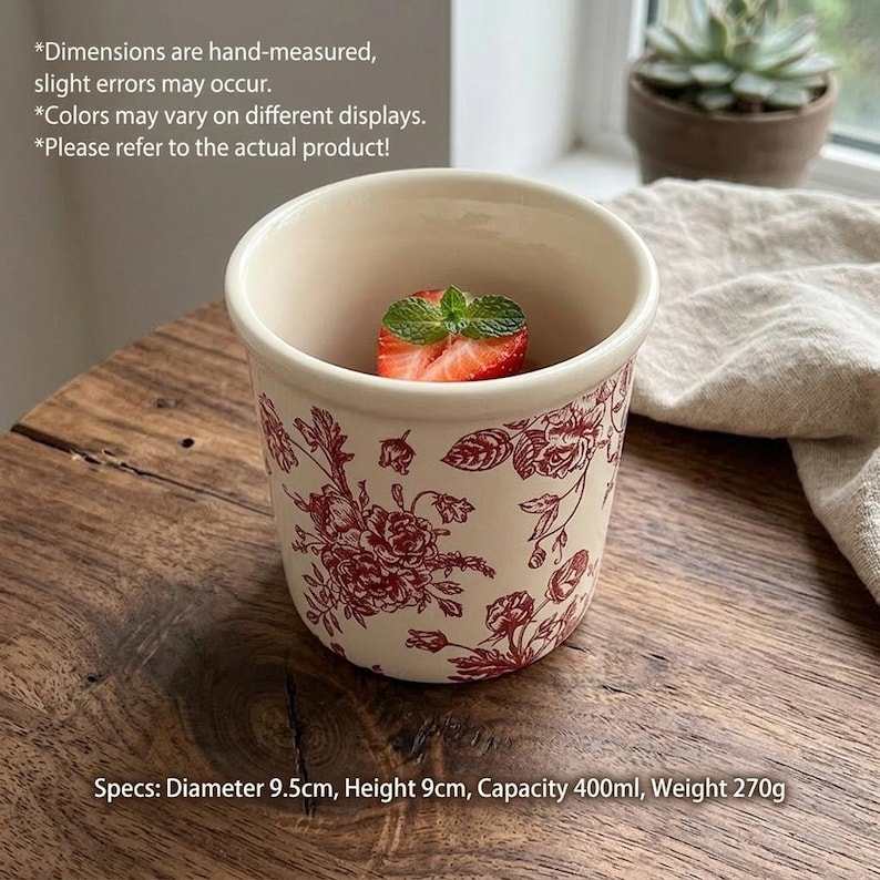 May include: Cream-colored ceramic mug with a red floral pattern. The mug, 3.7 inches in diameter and 3.5 inches tall, contains a strawberry slice and mint. The mug's capacity is 13.5 fluid ounces and weighs 9.5 ounces.