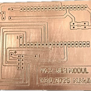 May include: A copper-coloured printed circuit board with etched pathways and numerous connection points. The board features the text "MCZ-WIFI MODUL V2.0 2025 M.Walle". The design includes rectangular pads and traces, suggesting an electronic component.