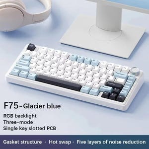 May include: A white and light blue mechanical keyboard with black and gray keys. The keyboard has the text "F75-Glacier blue" and "RGB backlight" printed on it. The keyboard is on a light blue surface.