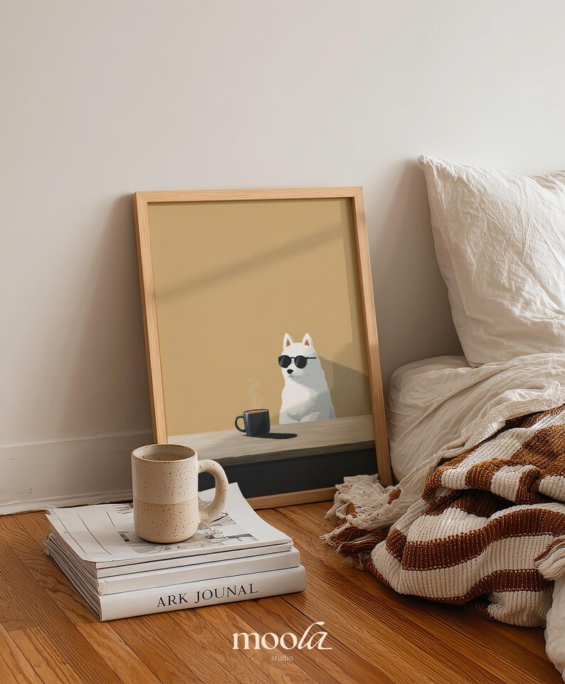 May include: A framed art print featuring a white dog wearing sunglasses, sitting at a table with a coffee cup. A stack of books and a speckled mug are in front of the print. The print is in a light wood frame. The word "moola" is in the bottom right corner.