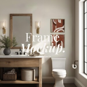 May include: A bathroom interior with a wooden vanity, mirror, and sconces. Two framed abstract art pieces hang on the wall. A toilet and a window are also visible. The text "Frame Mockup" is displayed.