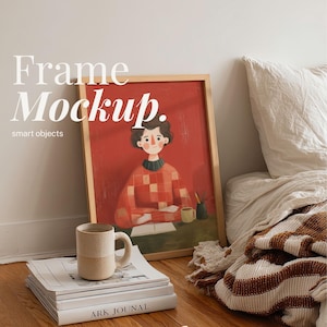 May include: A framed artwork with a red background and a person illustration, leaning against a white wall. A stack of books, a mug, and a pencil holder are in front of the frame. The text "Frame Mockup" is at the top of the image.